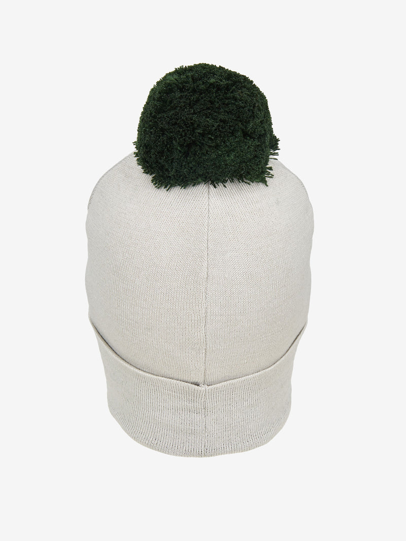 Ein weißer Strickbeanie mit einem grünen, plüschigen Bommel an der Oberseite, frontal betrachtet.