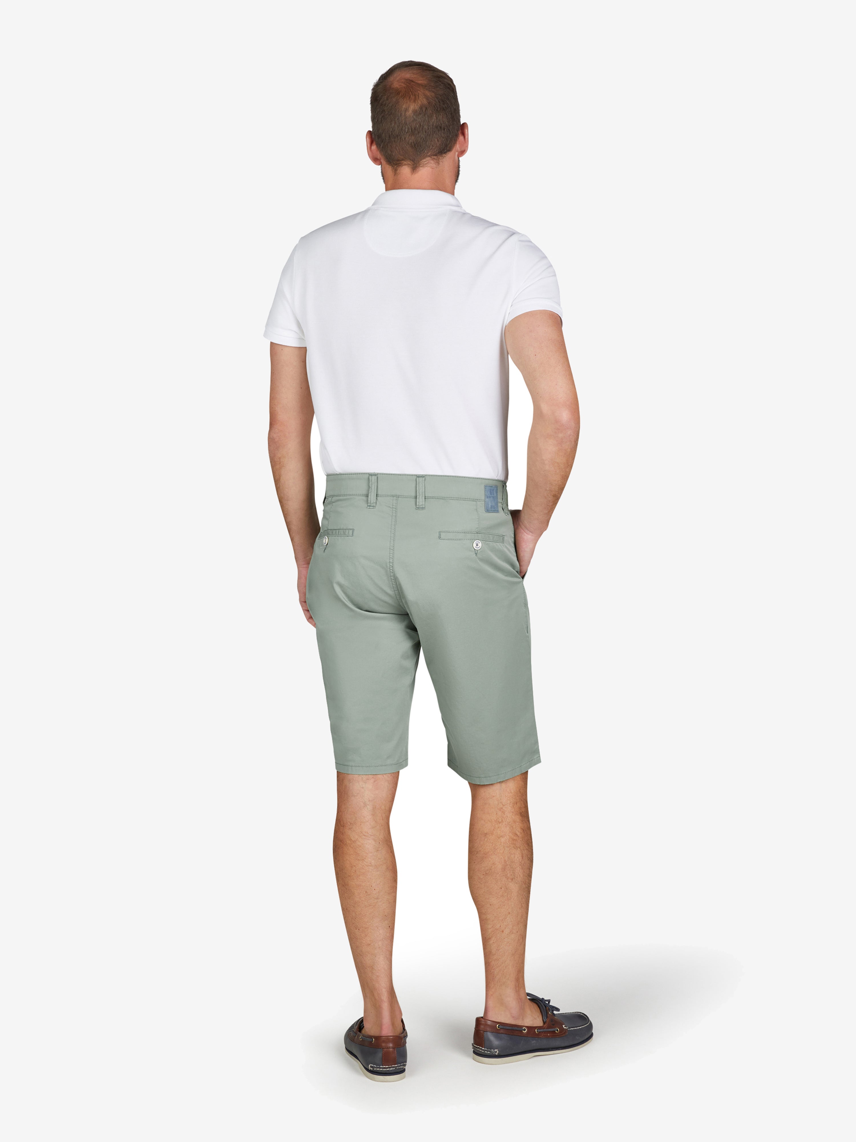 Mann trägt hellgrüne Bermuda-Shorts von Club of Comfort mit elastischem Comfortbund, Hemdenstopper, High Stretch aus Baumwoll-Tencel®-Mix, normale Leibhöhe, im Rückansicht, Frühjahr/Sommer, model steht auf weißem Hintergrund.