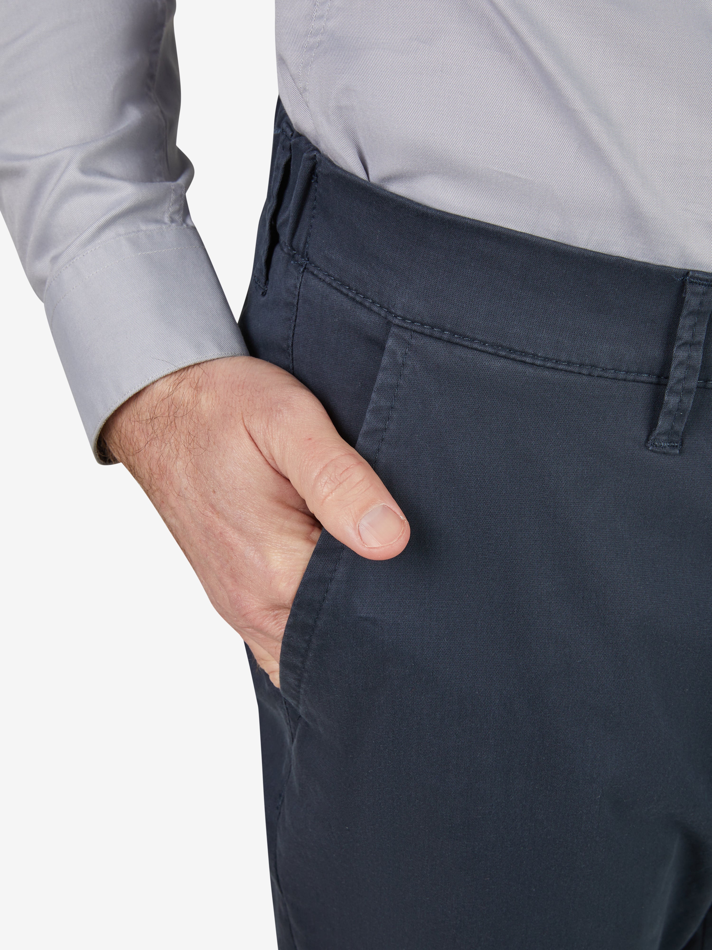 Nahaufnahme einer blauen Chino-Hose von Club of Comfort mit Komfortbund, Hemdenstopper und schmalem Bein, getragen von einer Person in hellgrauem Hemd. Die Hose besteht aus sommerleichter Baumwolle in High-Stretch-Qualität, perfekt für Frühjahr/Sommer.