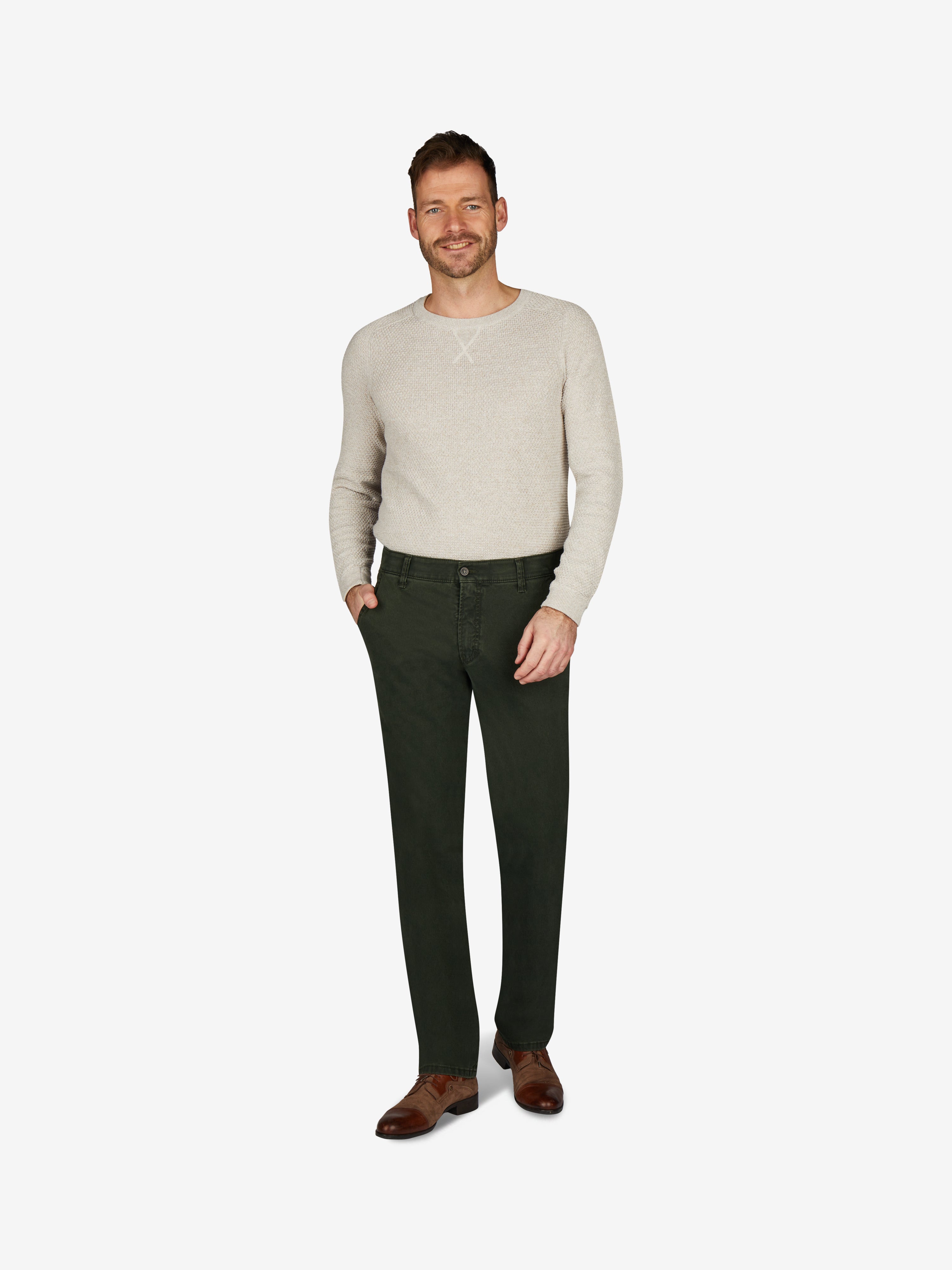Männlicher Model trägt dunkelgrüne GARVEY 6421 Flat Front-Hose mit elastischem Komfortbund, Hemdenstopper und schmaler Fußweite, kombiniert mit einem cremefarbenen Pullover, auf weißem Hintergrund.