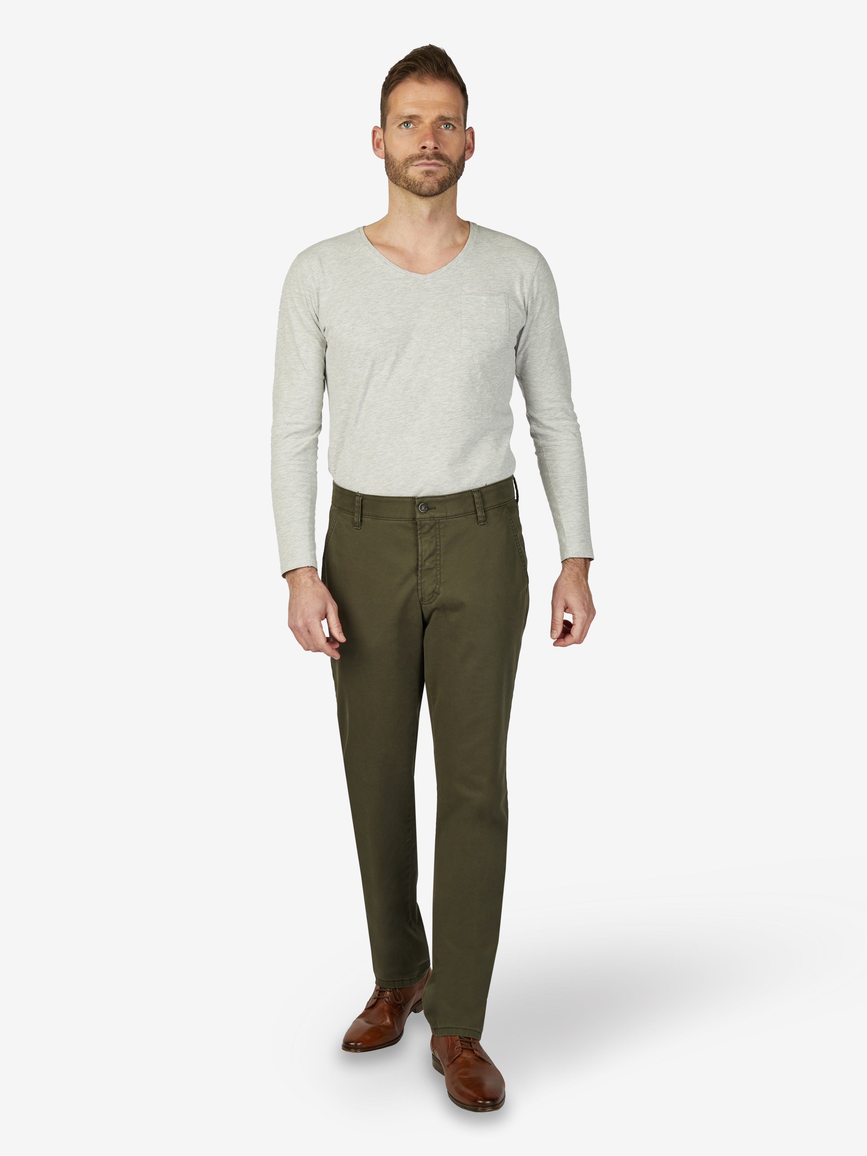 Männermodell trägt dunkelkhakifarbene GARVEY 6421 Flat Front-Hose mit elastischem Komfortbund, Hemdenstopper und schmaler Fußweite, aus hochelastischem Baumwoll-Gabardine, mit softem Griff, Regular Fit, ideal für Herbst/Winter, in Grün, Made in Green by Oeko-Tex.