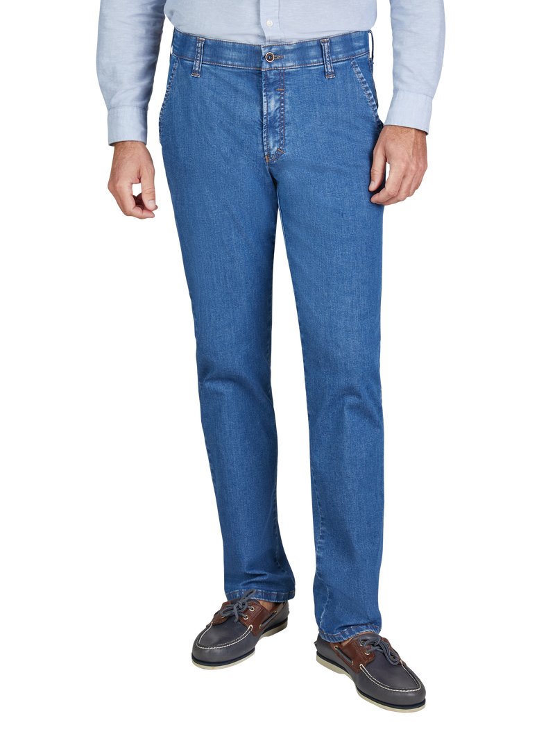 Hälfte eines Mannes, der blaue Jeans und braune Schuhe trägt, sichtbar. Er trägt eine helle, lange Hemd-Kleidung und steht vor einem weißen Hintergrund.