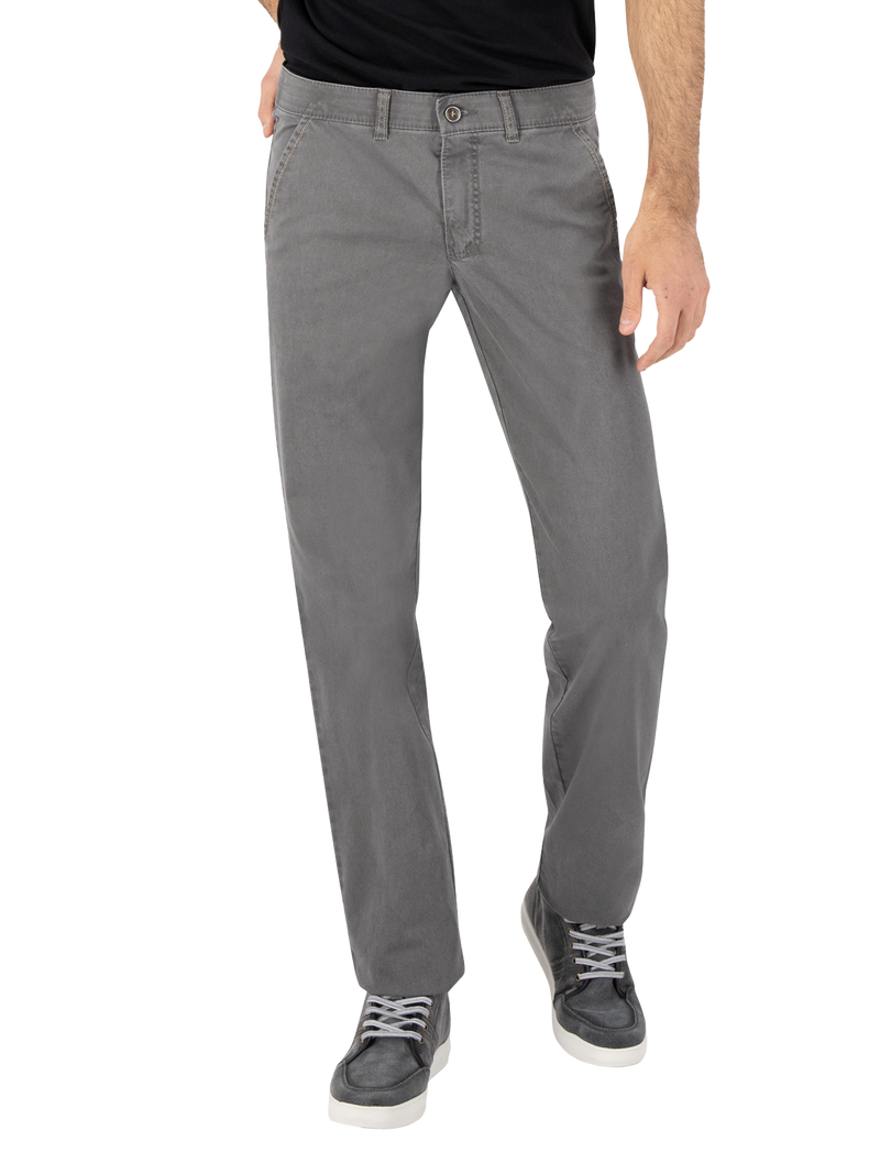 Blick auf die unteren Körperhälfte eines Mannes, der eine schwarze T-Shirt trägt, graue Jeanshose und dunkelgraue Sneakers mit weißen Sohlen. Die Person steht mit leicht gespreizten Beinen.