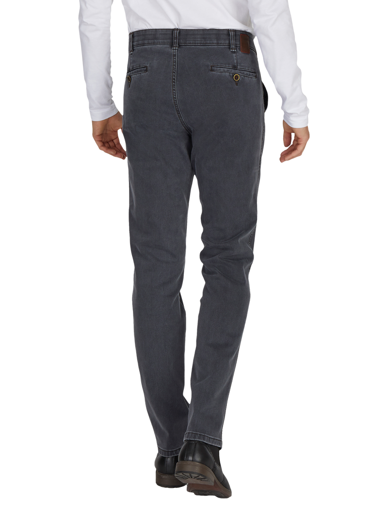 Herrenhose aus dunklem Jeansstoff, schmal geschnitten mit Gürtel und Goldknöpfen an den Taschen, getragen von einer Person in schwarzem Schuhwerk und weißem Hemd.