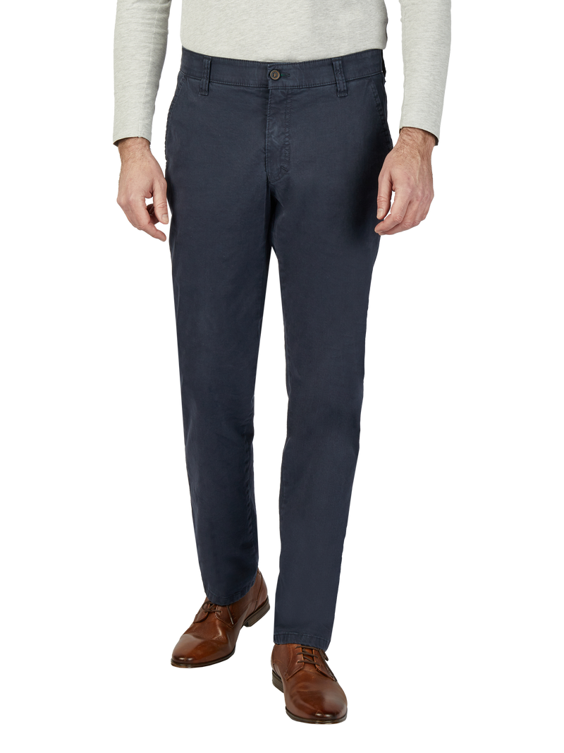 Nahaufnahme eines Mannes, der dunkle, gleichmäßig sitzende Chino-Hosen trägt. Er trägt eine hellgraue Langarmhose und braune Lederschuhe.