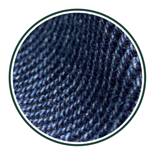 Nahaufnahme eines dunkelblauen Jeansstoffs mit sichtbarer diagonaler Webstruktur und leichten Farbvariationen, die die Textur und das Material betonen.