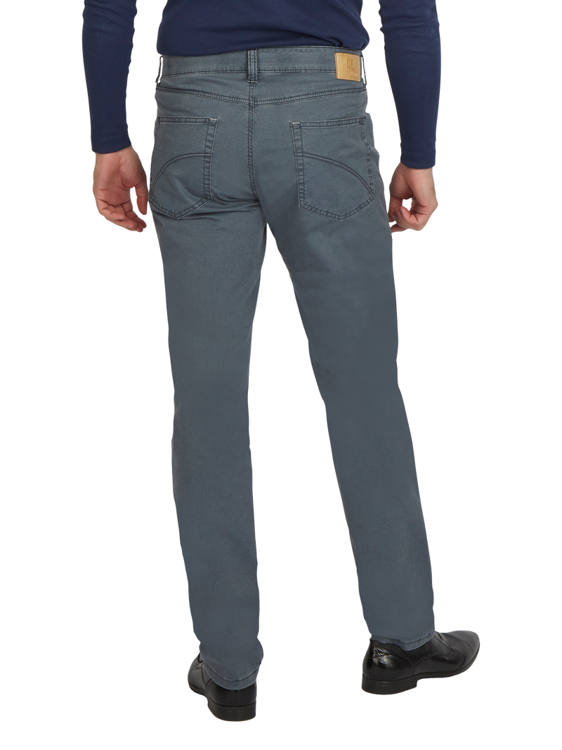 Herrenjeans in dunklem Blau, sichtbar von hinten. Der Jeansstoff hat eine leichte Waschung, mit zwei Rückentaschen und einem braunen Lederlabel am Bund auf der rechten Seite. Der Mann trägt schwarze Schuhe und ein dunkelblaues Oberteil.