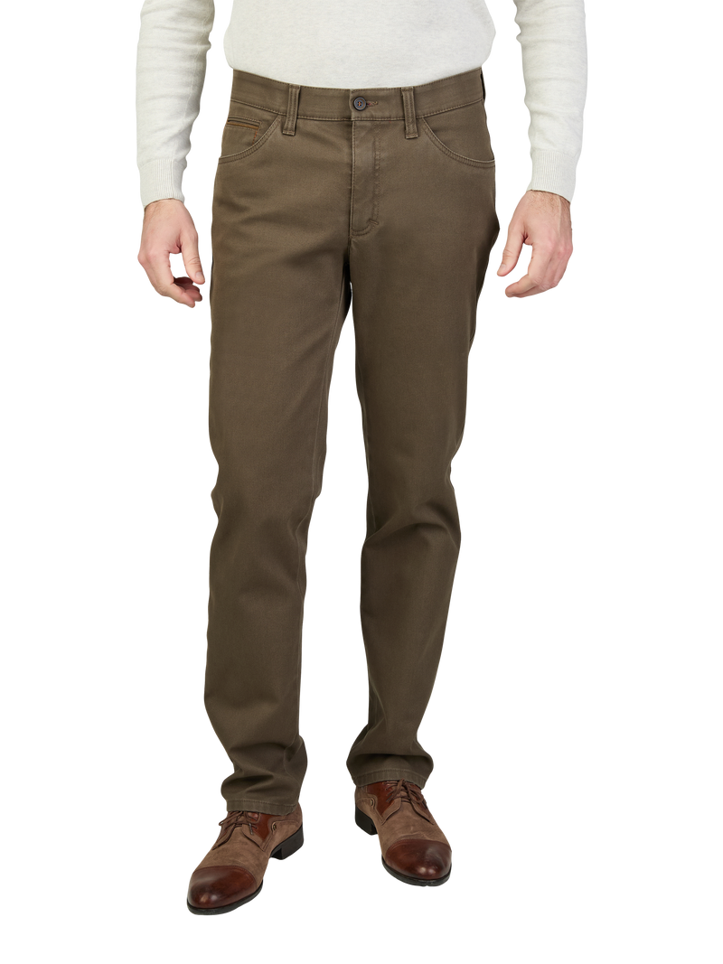 Nahaufnahme der unteren Körperhälfte eines Mannes in braunen Chino-Hosen, weißem Pullover und braunen Lederschuhen, auf hellem Hintergrund.