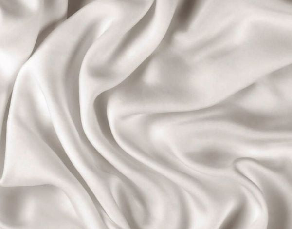Weiches, glänzendes weißes Satin- oder Seidenstoffstück mit sanften Falten und Wellen, das einen eleganten und luxuriösen Eindruck vermittelt.