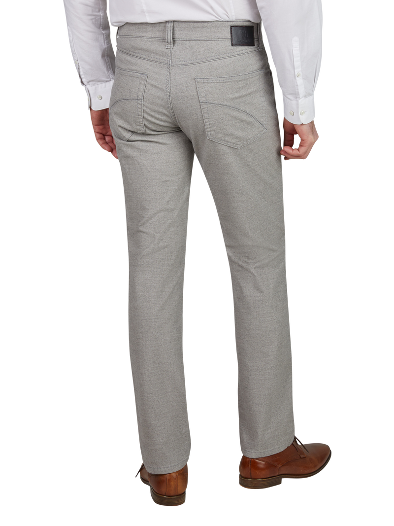 Rückansicht einer Person, die ein hellgraues Paar Anzughosen, ein weißes Hemd und braune Lederschuhe trägt.