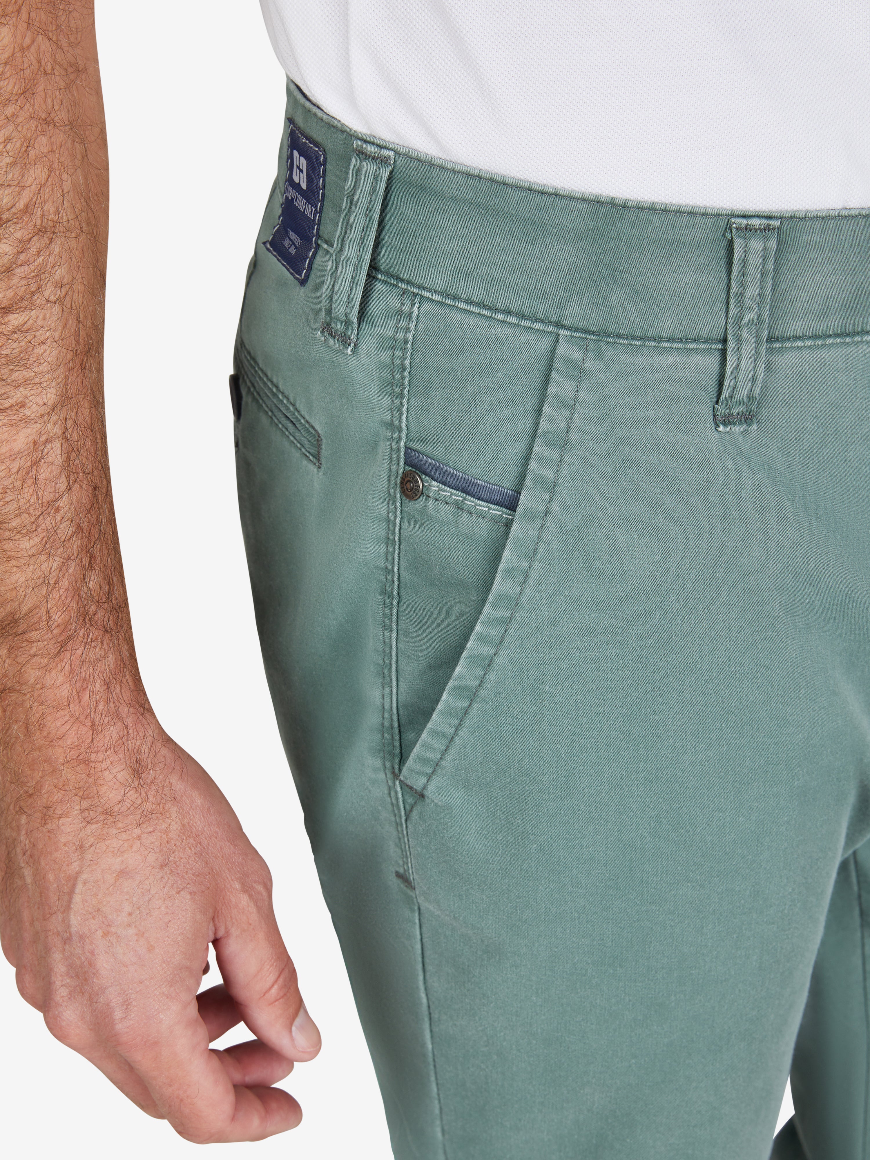 Nahaufnahme einer blaugünnen Flat Front-Hose mit elastischem Komfortbund, Hemdstopper und Münztasche rechts. Das Produkt ist leicht, aus recyceltem Baumwoll-High Stretch mit Fade Out-Färbung und Coolmax EcoMade Klimaregulierung. Marke: Club of Comfort, Modell GARVEY 7323.