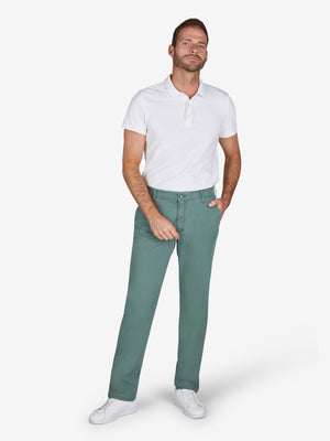 Mann trägt eine grüne GARVEY 7323 Flat Front-Hose aus Baumwolle mit High Stretch, Komfortbund und Hemdstopper, Modell Regular Fit, kombiniert mit weißem Polo-Shirt. Die Hose hat eine schmale Beinpassform, Münztasche rechts, und ist für Frühling/Sommer ideal.